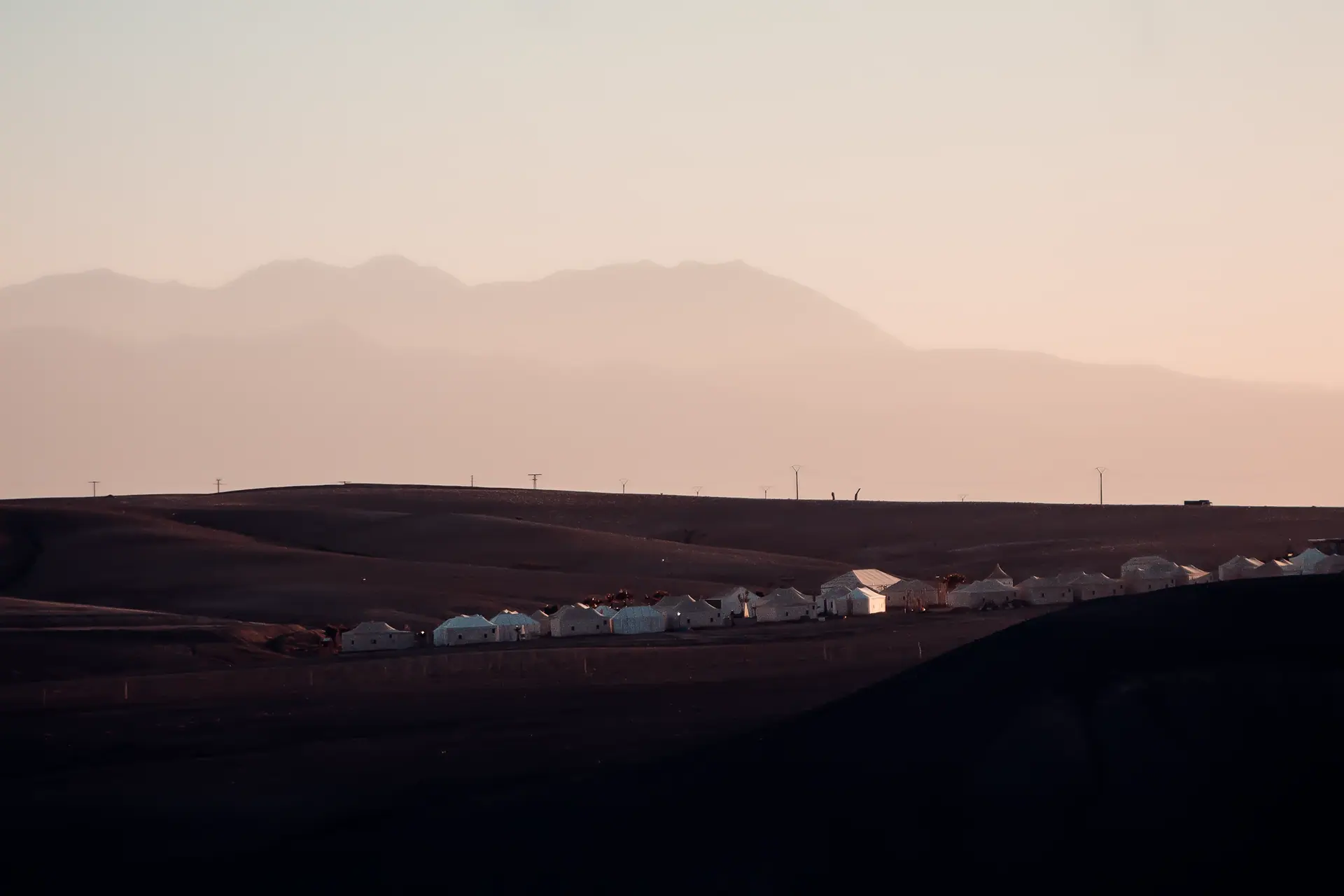 Explore the serene beauty of a village at sunset in Agafay Desert, Morocco.