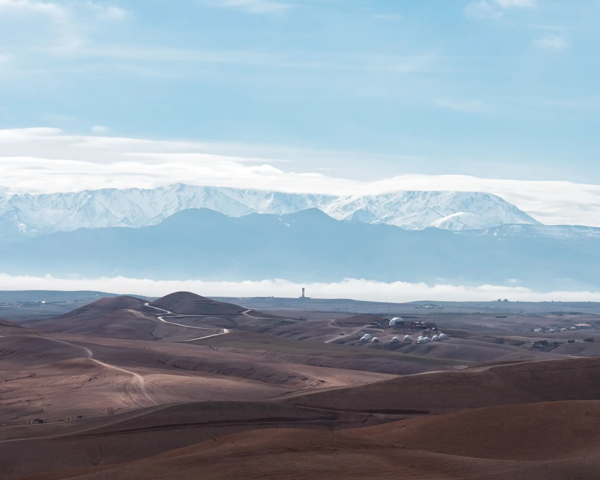 Breathtaking shot of Agafay Desert landscape with snow-capped Atlas Mountains.