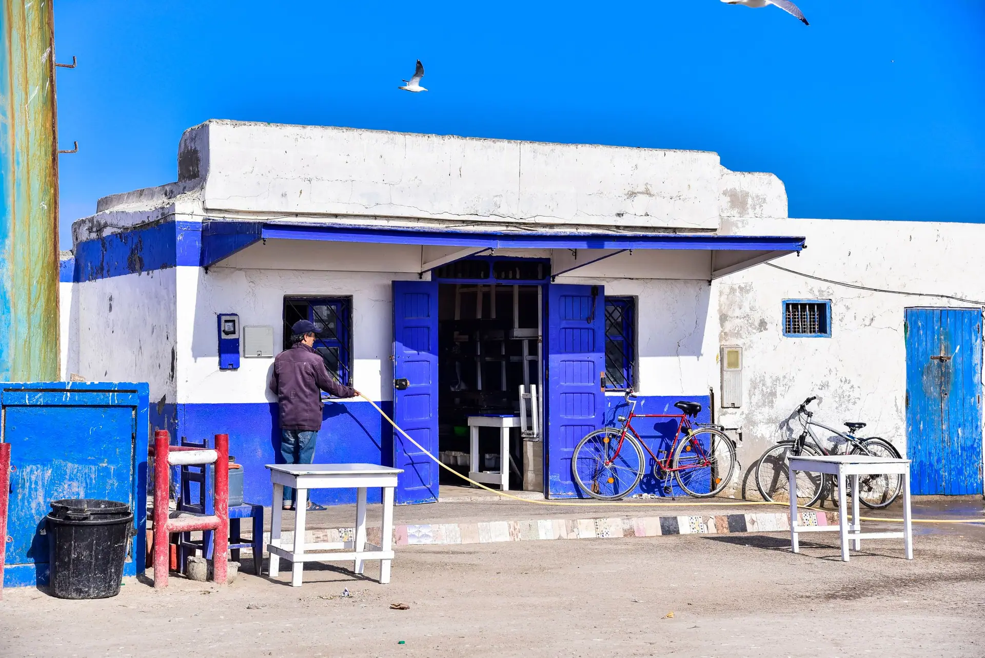 A vibrant blue and white building with bicycles in Essaouira, Morocco on a sunny day.