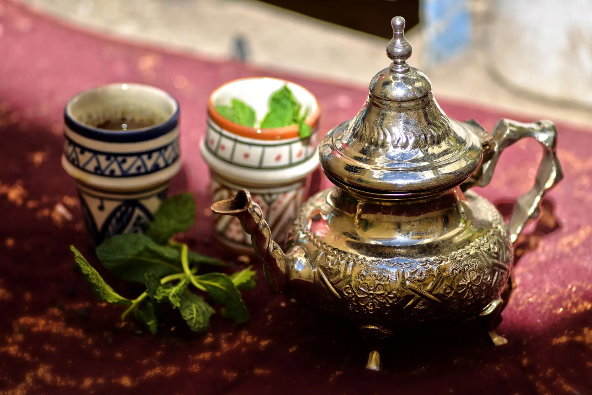 A traditional Moroccan mint tea set with a silver teapot and cups outdoors in Fès, Morocco.
